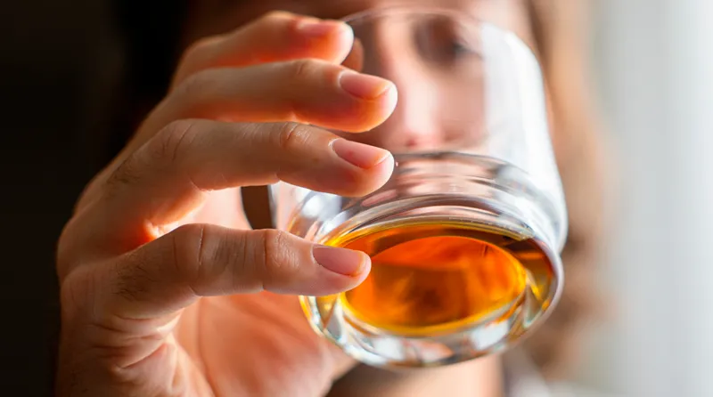 Мужчина держит стакан алкоголя